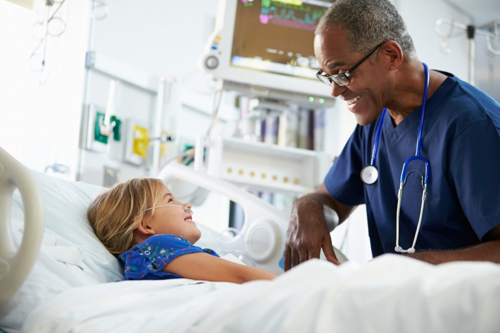 Stock image of an older African American doctor caring for a young girl in a hosptial.